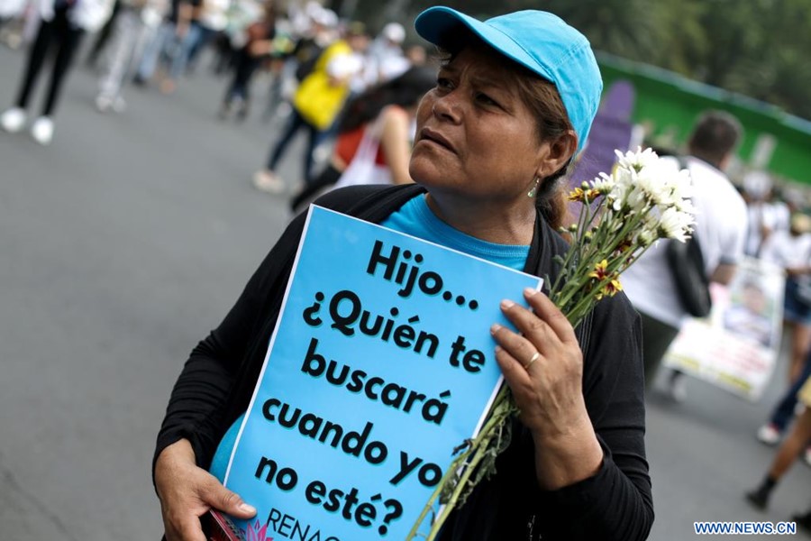  Una mujer sostiene un cartel y flores mientras participa en una marcha en el marco del Día de las Madres, en la Ciudad de México, capital de México, el 10 de mayo de 2023. El Día de las Madres se celebra anualmente en México el 10 de mayo. (Xinhua/Francisco Cañedo) 