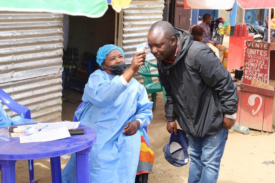 Imagen del 23 de mayo de 2026 de una trabajadora de la salud tomando la temperatura corporal de un residente en el punto de revisión de la entrada a Bunia, en la provincia de Ituri, en la República Democrática del Congo (RDC). (Xinhua/Str)