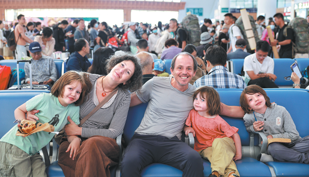 Turistas franceses aguardan el viernes en la estación ferroviaria de Kunming Sur para abordar el tren de alta velocidad China-Laos con destino a Xishuangbanna, en la provincia de Yunnan, suroeste de China. Yunnan se ha convertido en un destino muy popular tanto para viajeros nacionales como extranjeros que buscan escapar del calor y disfrutar de sus vacaciones de verano. YANG ZIXUAN/XINHUA