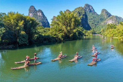 Turistas navegan en balsas de bambú para disfrutar del paisaje a orillas del río Yulong, en la zona paisajística del río Yulong, condado de Yangshuo, Guilin, en la región autónoma zhuang de Guangxi, en el sur de China, el 7 de octubre de 2026. (Foto: Jiang Keqing)